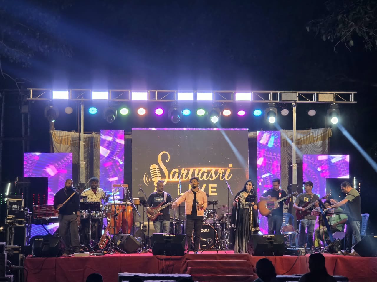 Sarvasri Live band performing on a brightly lit outdoor stage