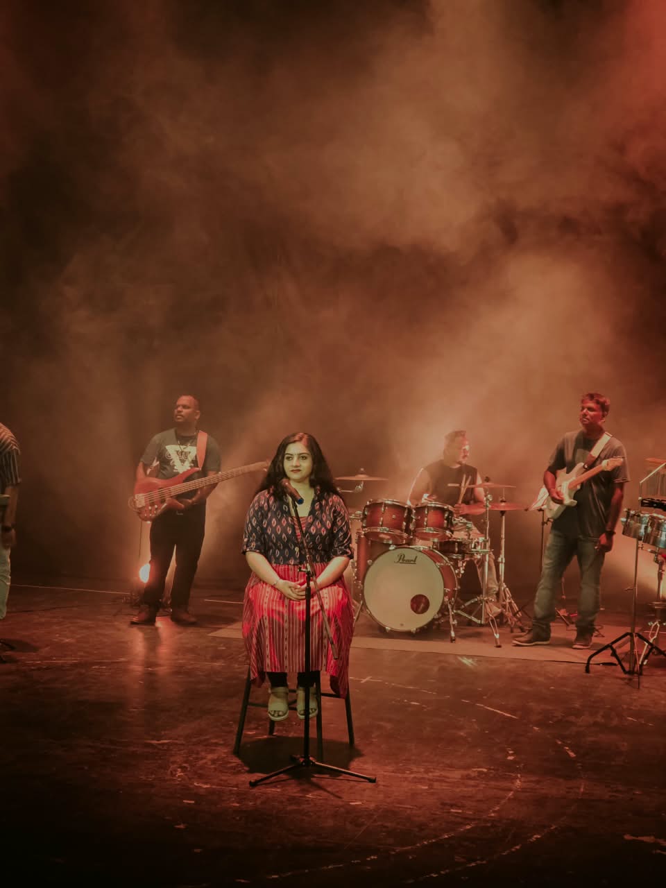 Sarvasri Sukesh seated on stage with her live band